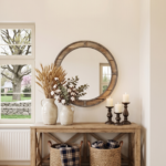 Modern farmhouse entryway featuring a wooden console table, large round mirror, ceramic vases with dried wheat, and woven storage baskets.